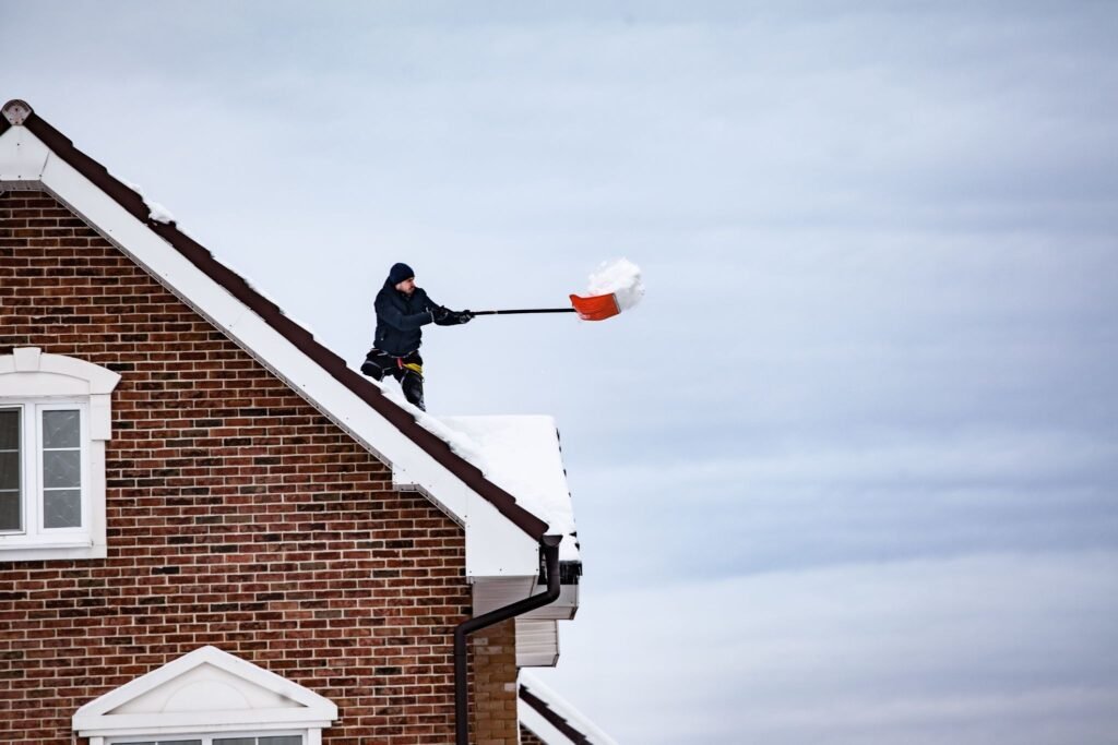 Man shoveling snow off of a roof